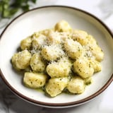 A bowl of pasta with cheese on top.