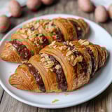 A plate of croissants with chocolate and nuts.