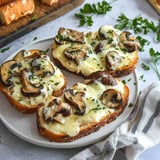 Two pieces of mushroom toast on a white plate.